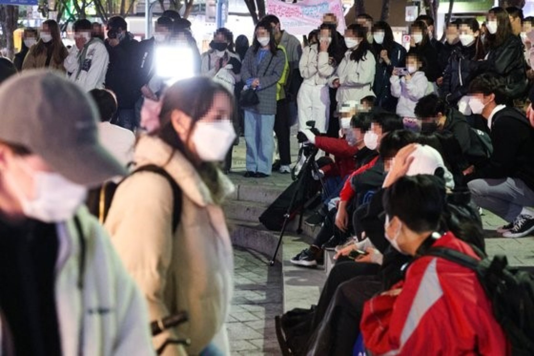 4月14日晚，市民们正在观看在首尔麻浦区弘益大学青春街举行的街头舞蹈表演。自从4月初韩国政府放宽保持社交距离措施以后，这些表演时隔3年再次出现在街头上。韩国政府决定从下周开始全面解除私人聚会限制和餐厅、咖啡厅营业时间限制等，取消大部分保持社交距离的防疫措施。【韩联社】